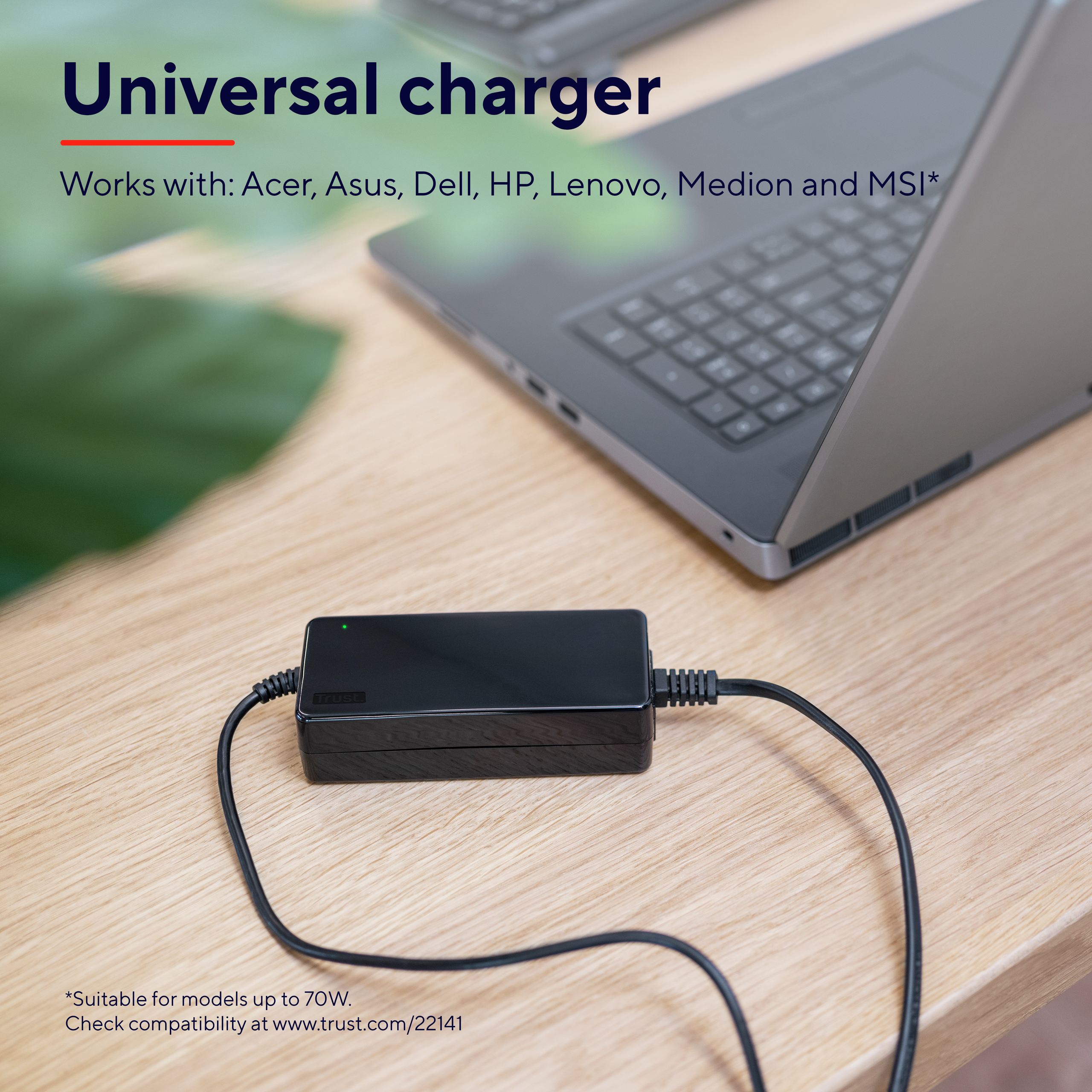 Chargeur noir avec câble, sur une table en bois avec un ordinateur portable, avec texte sur la compatibilité.
