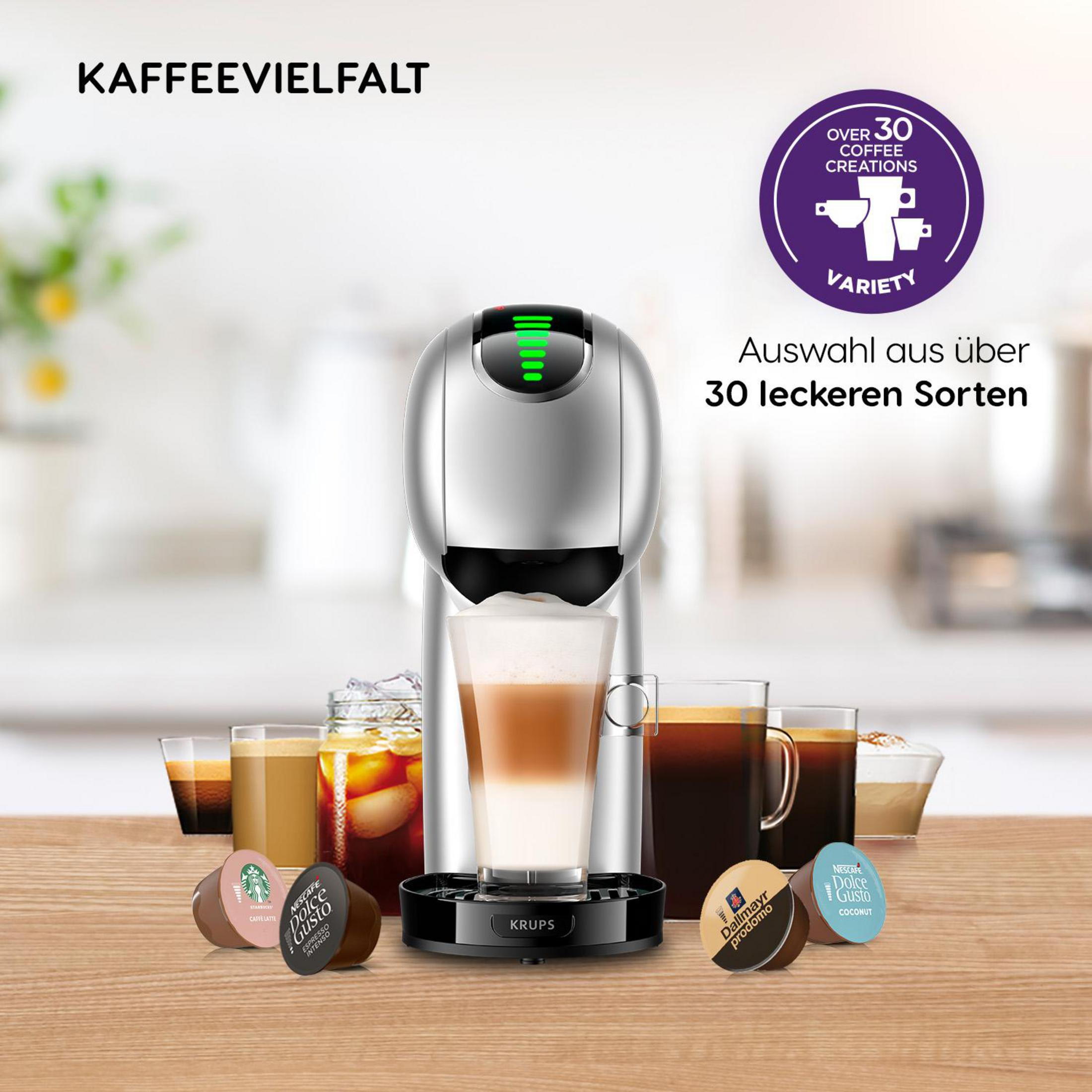 Kaffeemaschine mit einem Glas Latte und Kaffeepads, verschiedene andere Kaffeetassen im Hintergrund.