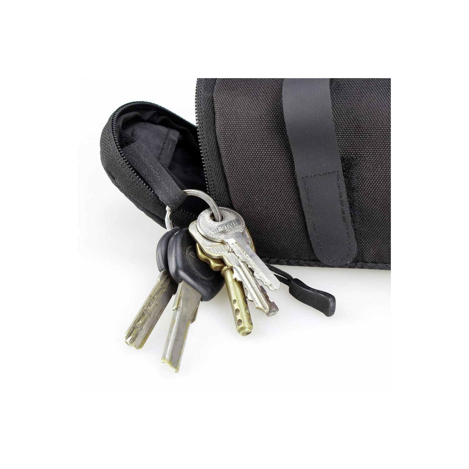 Schlüssel, die an einem schwarzen Reißverschlussbeutel hängen, der an einer schwarzen Tasche befestigt ist. Weißer Hintergrund.
