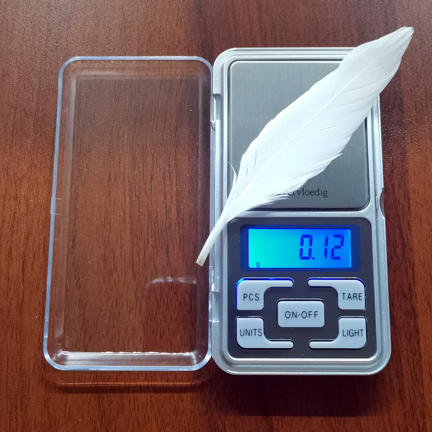 Digitale Waage mit Feder. Die Waage zeigt 0,12g an. Klares Gehäuse und braune Oberfläche.
