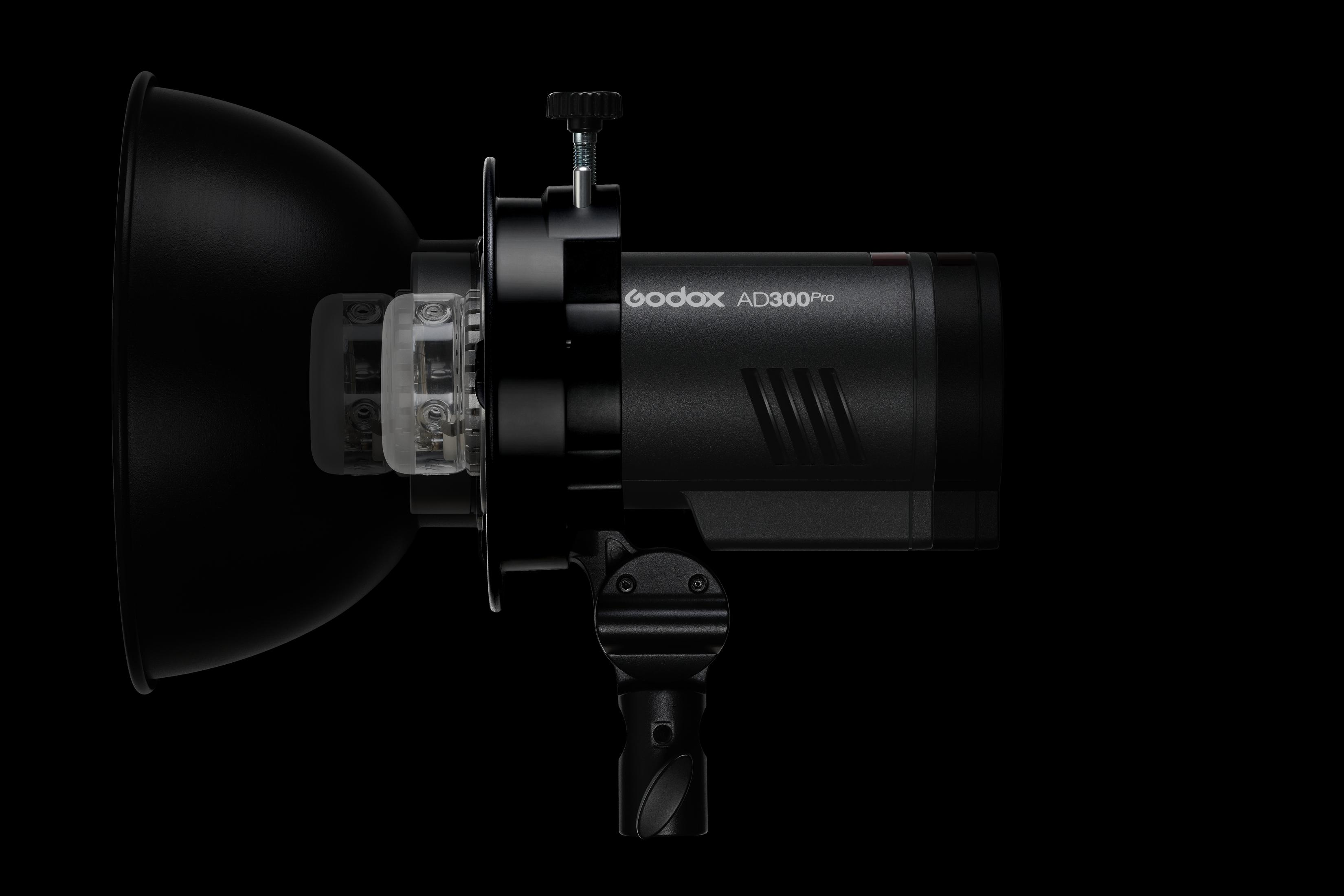 Czarna lampa błyskowa Godox AD300Pro z reflektorem i przezroczystą plastikową osłoną na czarnym tle.
