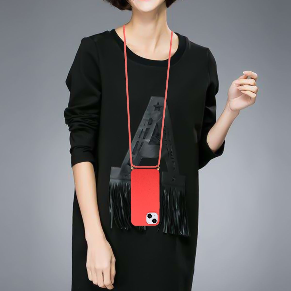 Frau trägt ein schwarzes Kleid, hält ein rotes Handy mit Lanyard. Grauer Hintergrund.