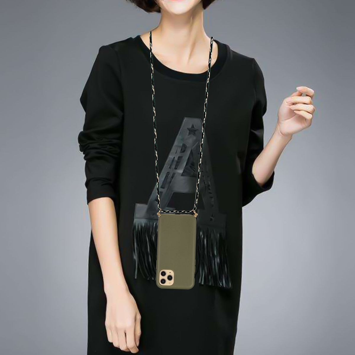Eine Frau trägt ein schwarzes Kleid mit einem großen A. Ein Telefon hängt an ihrem Hals.