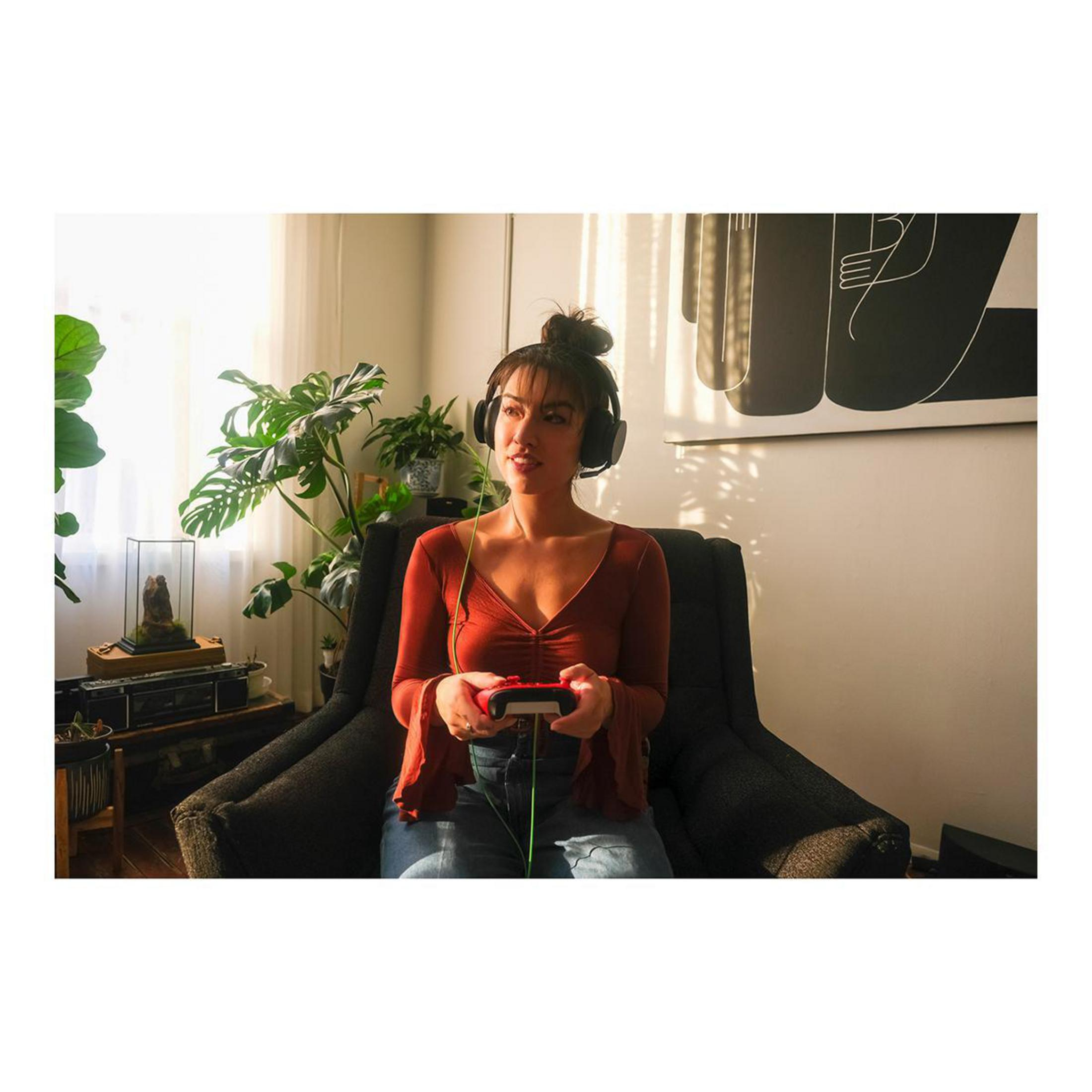 Donna con cuffie gioca a un videogioco con un controller.