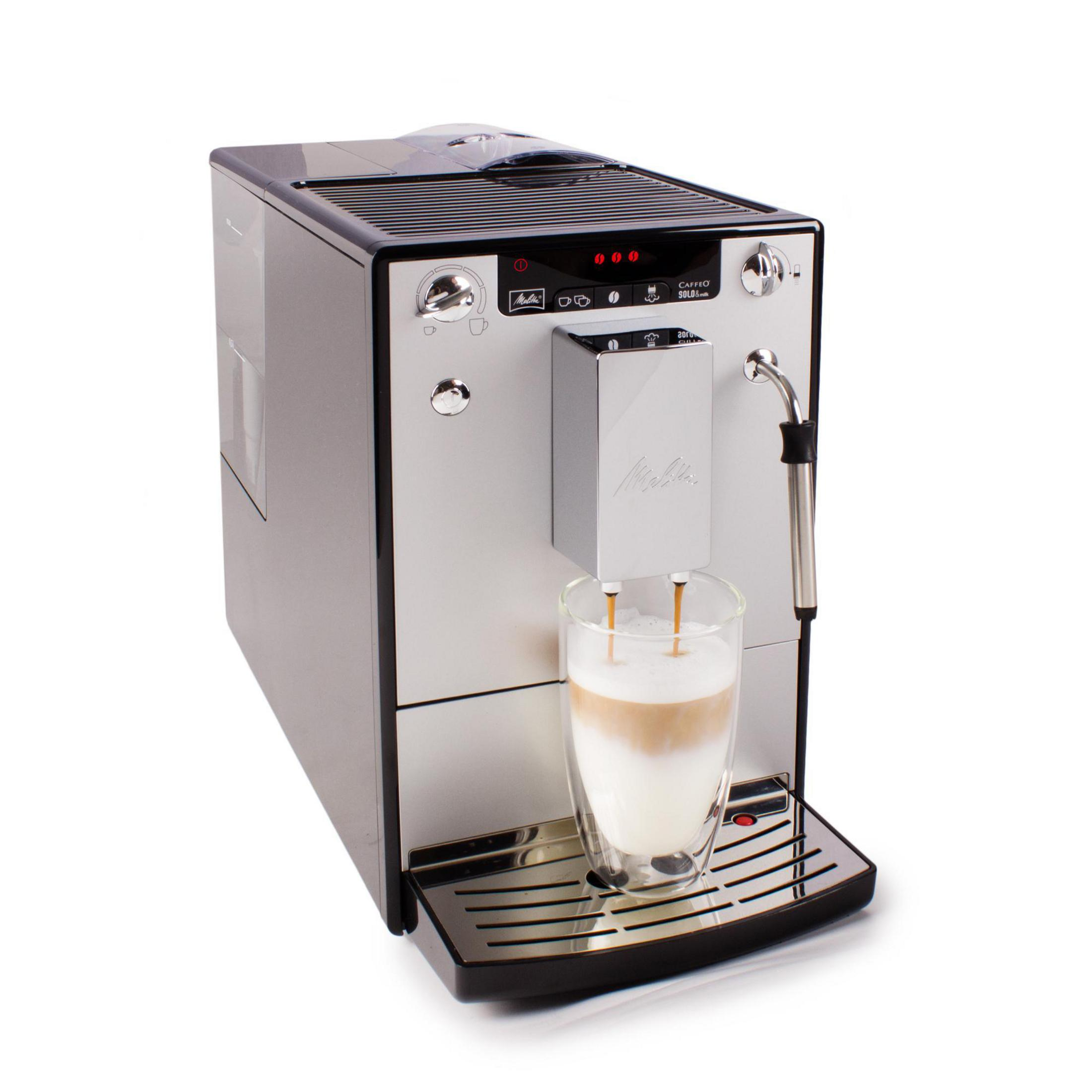Eine Kaffeemaschine, die Kaffee in eine Glastasse mit Milch ausgibt.