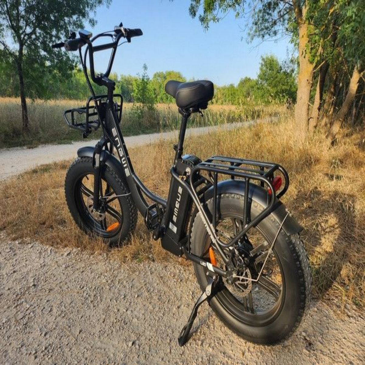 Bicicletta elettrica nera su uno sterrato; alberi sullo sfondo.