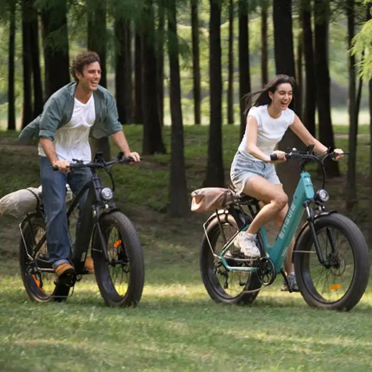 Due persone in bici elettriche in un parco, circondate da alberi ed erba.