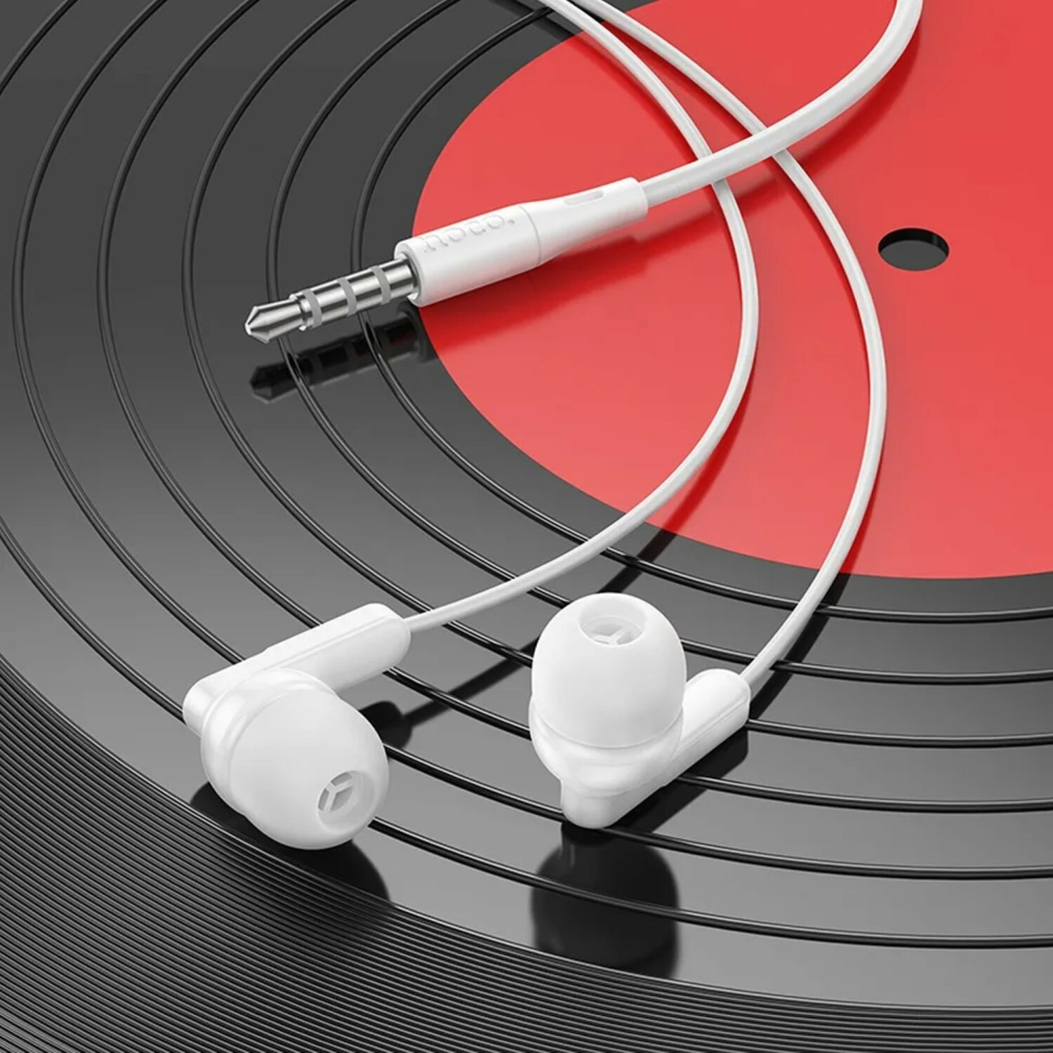 Auricolari bianchi con cavo bianco su un vinile rosso e nero.