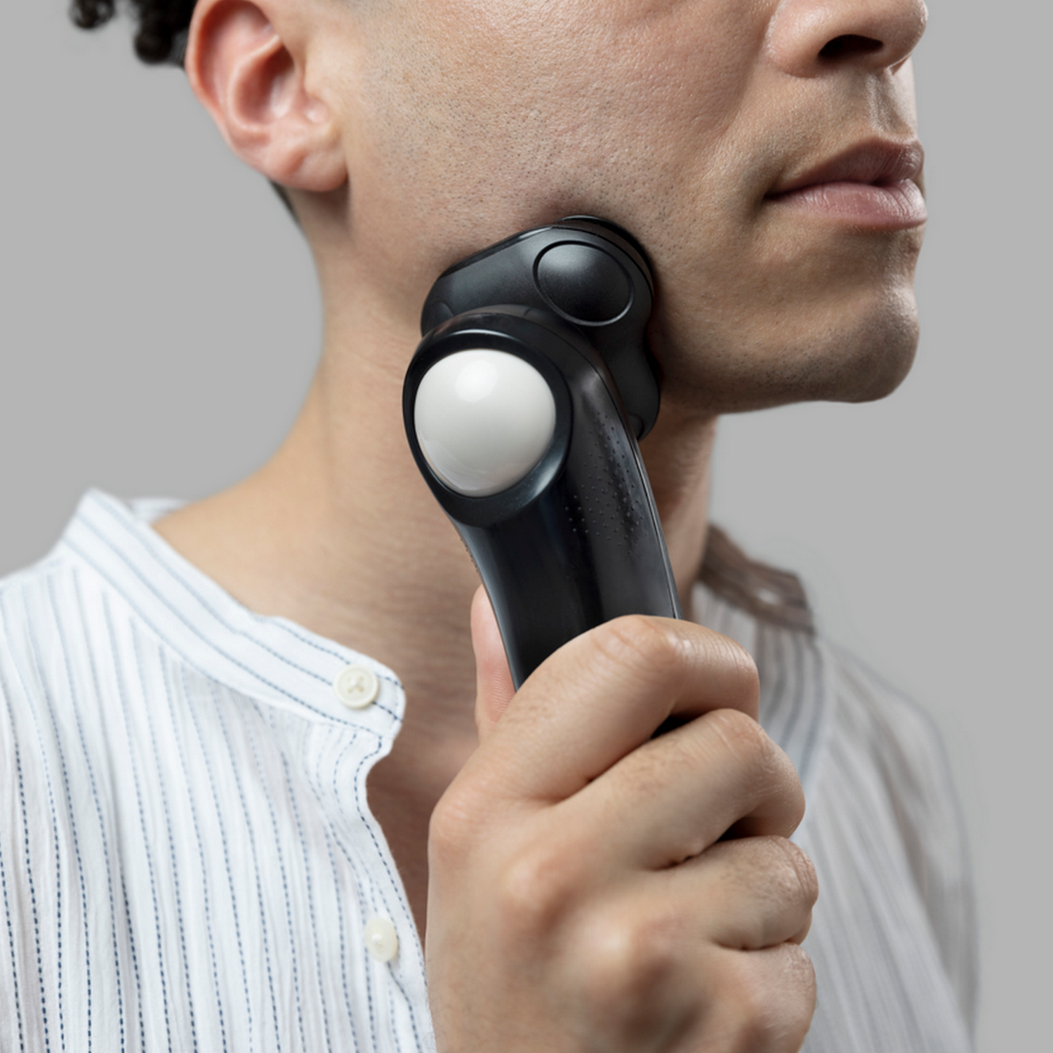 Uomo che si rade con un rasoio elettrico in bianco e nero.