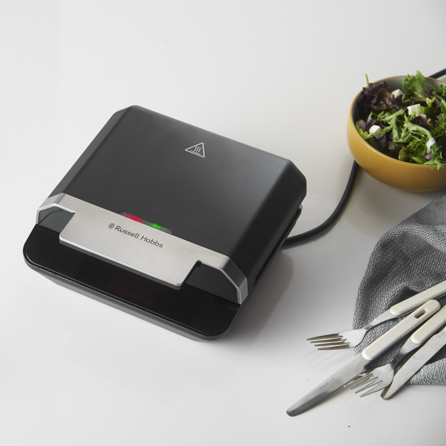 Black sandwich maker with a salad bowl and forks.