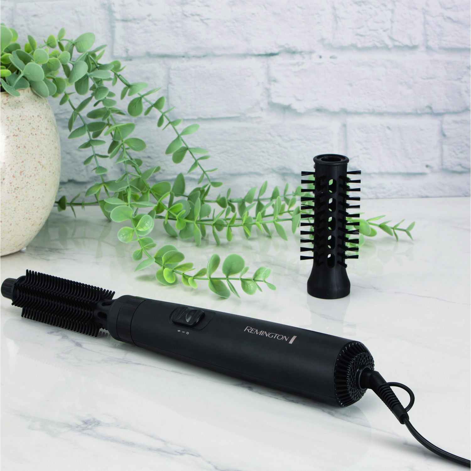 Czarna suszarka do włosów z dwoma nasadkami. Tło z białej ceglanej ściany.