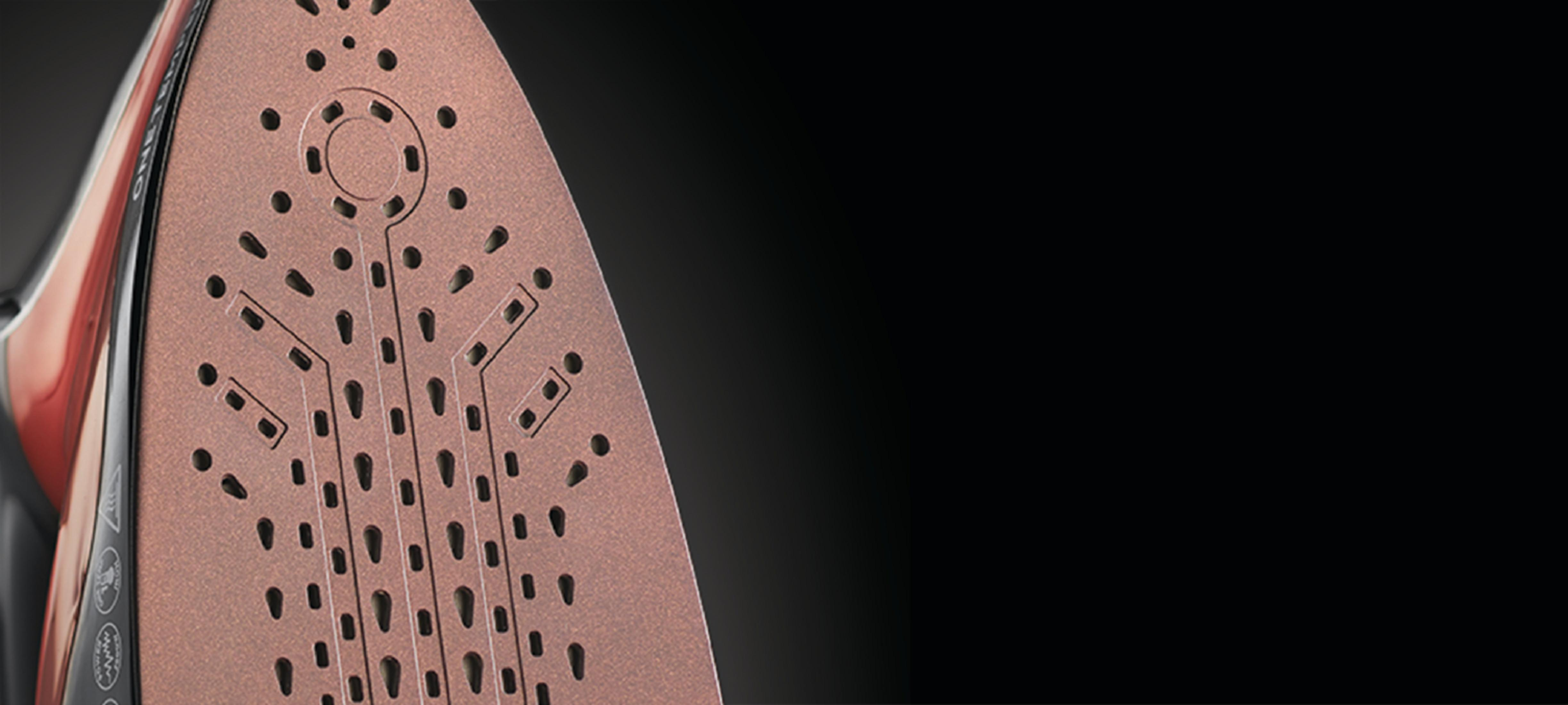 Zbliżenie stopy żelazka z perforacjami, na czarnym tle.