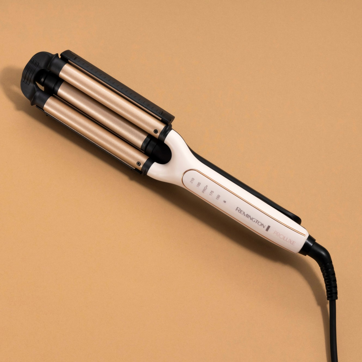 Złoto-czarna falownica do włosów na białej powierzchni.