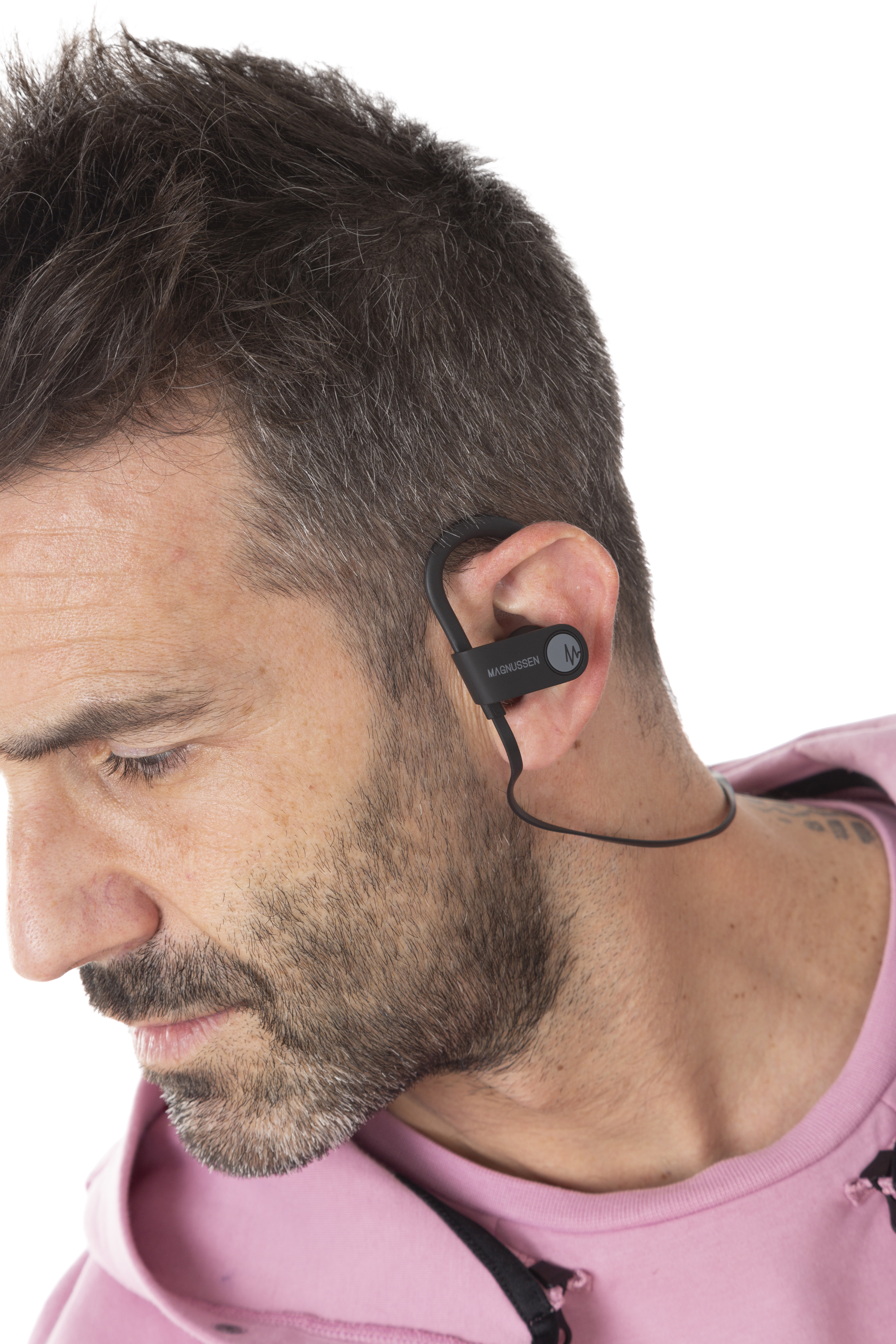Hombre con camisa rosa, usando un auricular inalámbrico Magnussen negro.