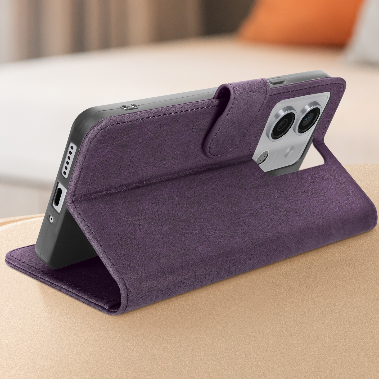 Una custodia per telefono in pelle viola con un telefono all'interno, aperta su una superficie chiara.