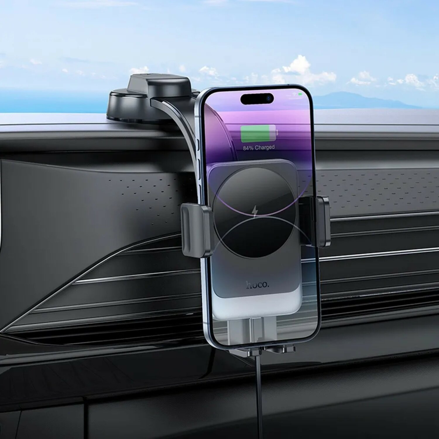 Ein Telefon, das in einer Autotelefonhalterung geladen wird. Der Bildschirm zeigt 84 % Ladung mit blauem Himmel im Hintergrund.