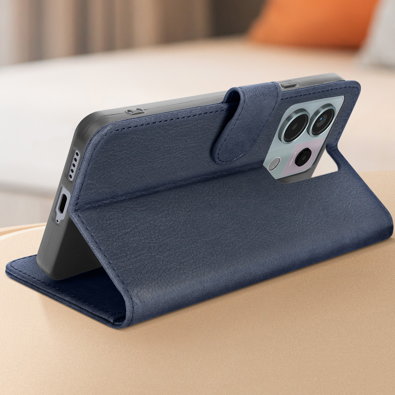 Custodia blu per telefono con telefono dentro, su un tavolo di legno. Sfondo: un letto.