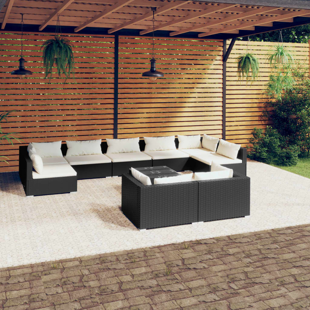 Terrassenset im Freien mit schwarzen Rattanmöbeln und weißen Kissen, Holzzaun im Hintergrund.