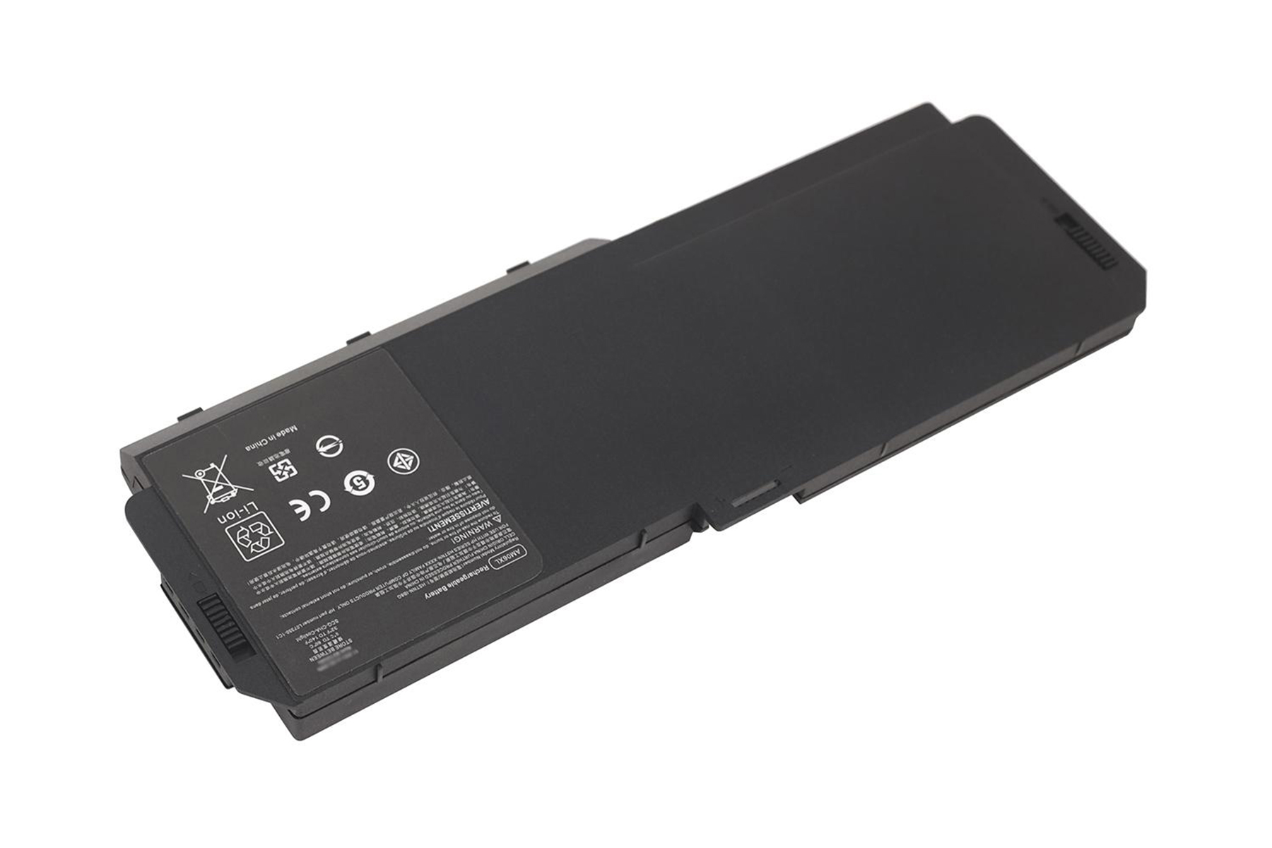 Una batteria per laptop nera è mostrata su una superficie bianca, con vari segni ed etichette visibili.
