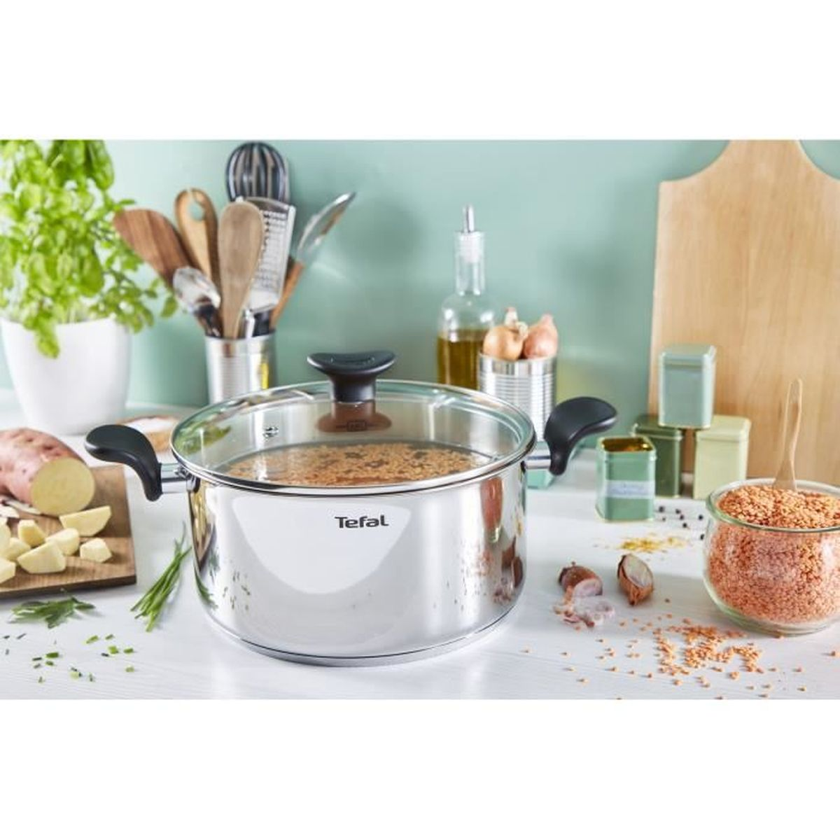 Ein Edelstahl-Tefal-Topf mit Gemüse und Zutaten, auf einer weißen Theke stehend.