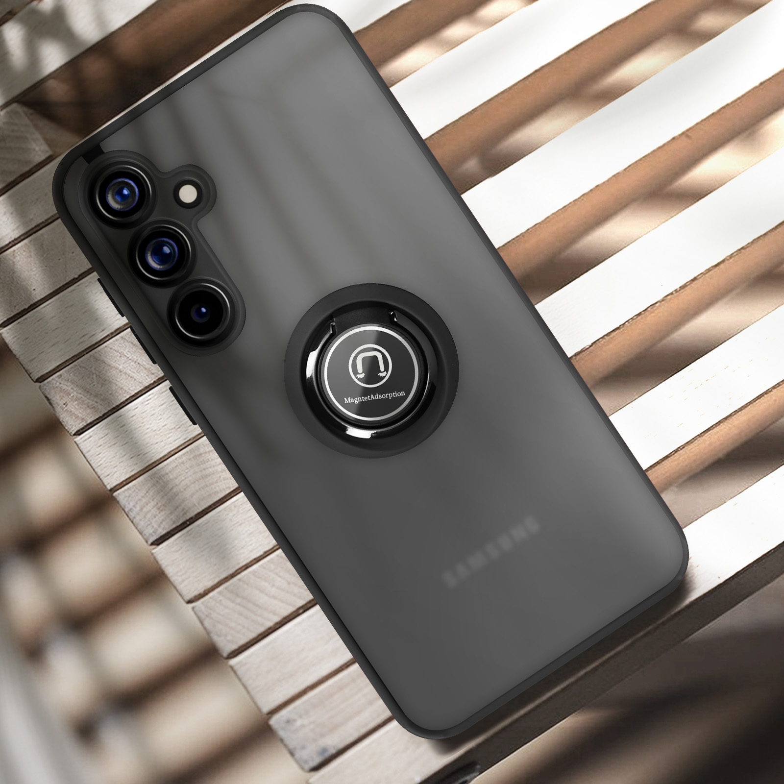 Una custodia nera per telefono con un porta anello è mostrata. La custodia è su una superficie di legno.