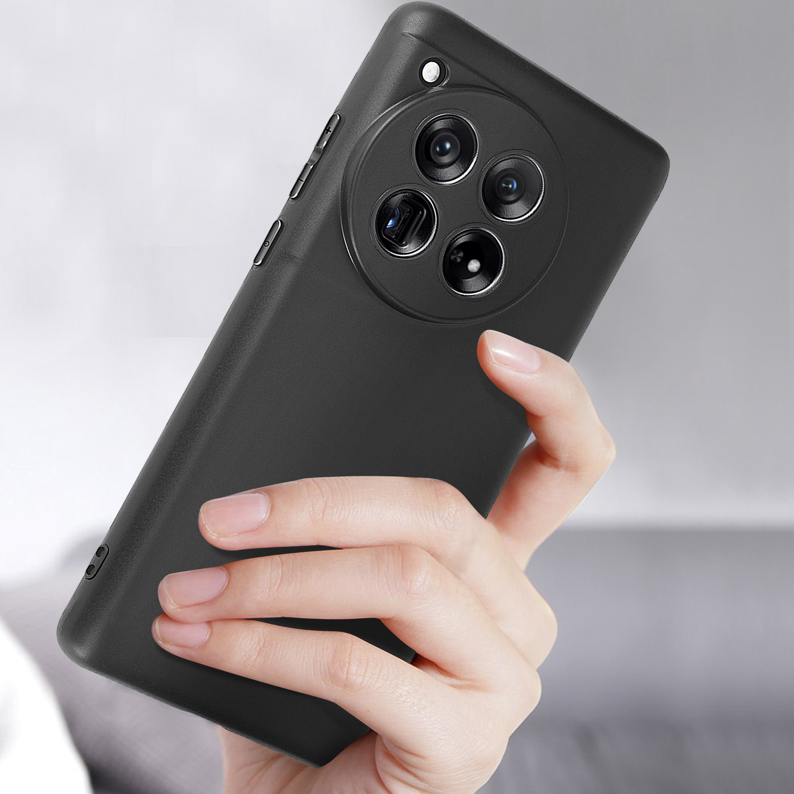 Una persona tiene in mano una custodia nera per telefono con tre lenti della fotocamera, pulsanti laterali.