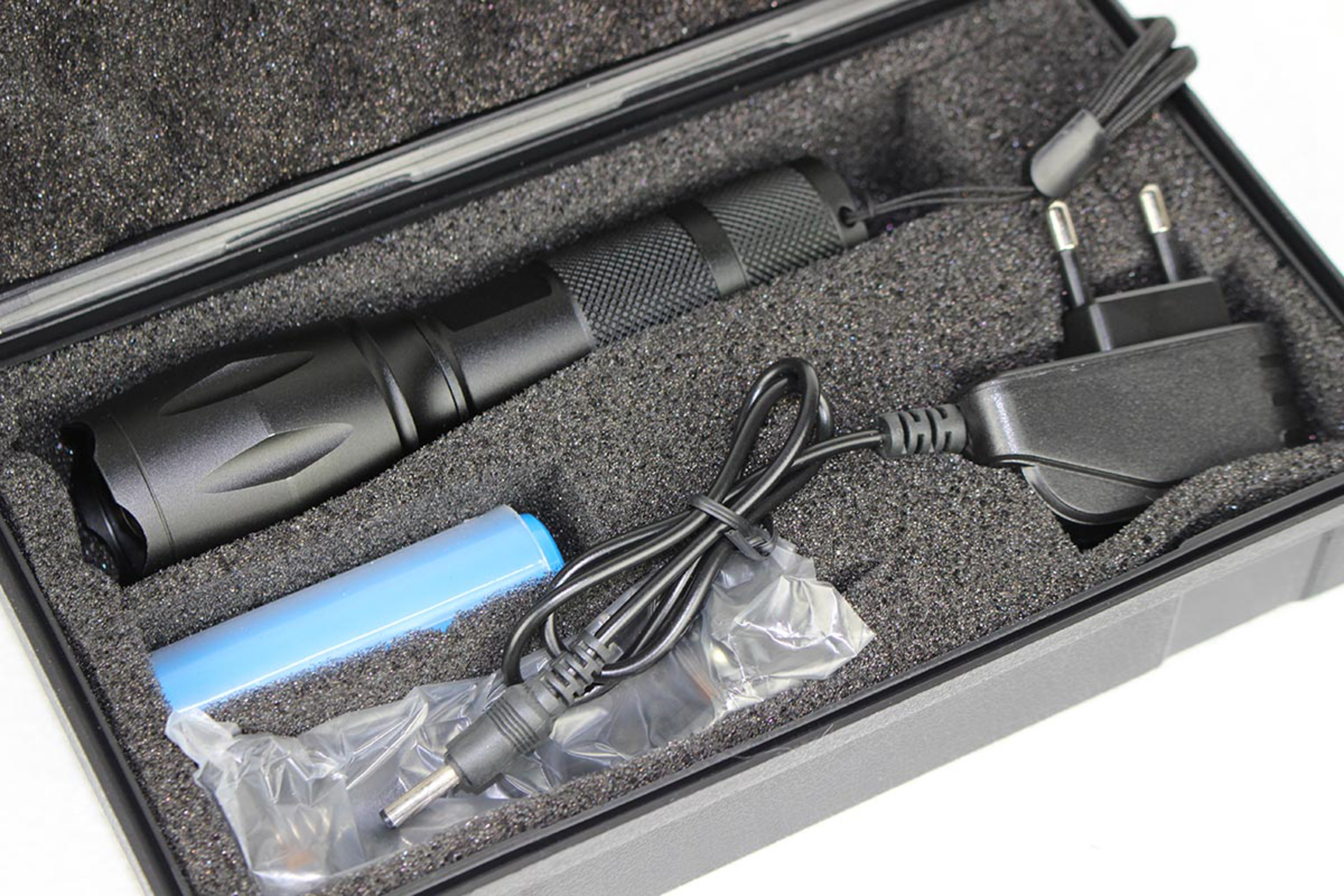 Eine schwarze Taschenlampe und Zubehör in einem Koffer. Enthält ein Ladegerät, einen Akku und Kabel.