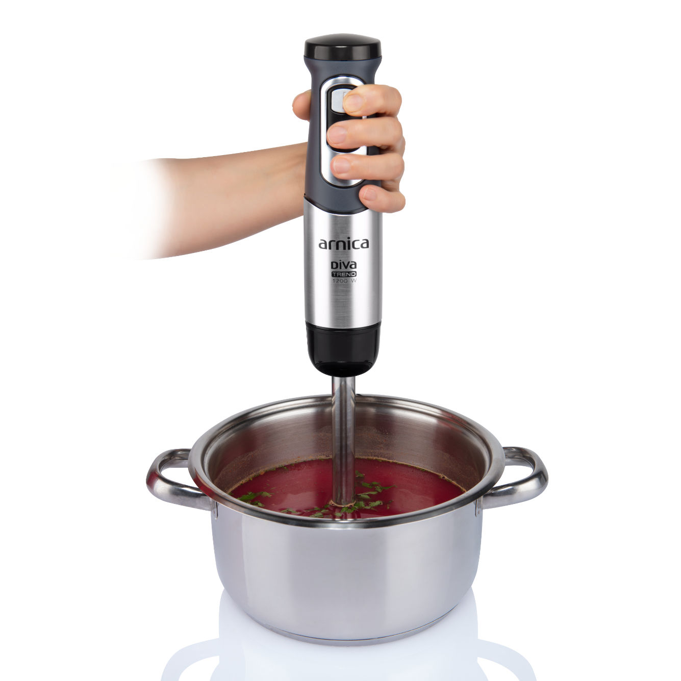 Hand hält Mixer in Topf mit rosa Suppe.