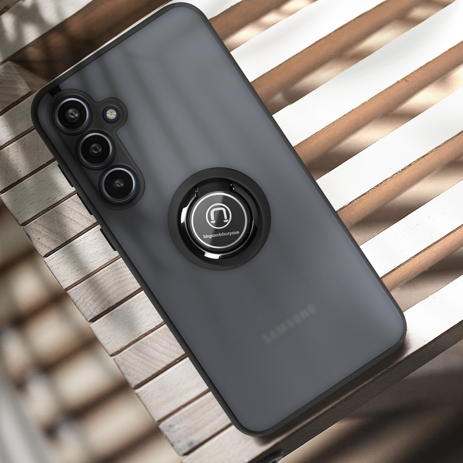 Custodia nera per telefono con anello sul retro, posizionata su una superficie in legno. Sfondo grigio.