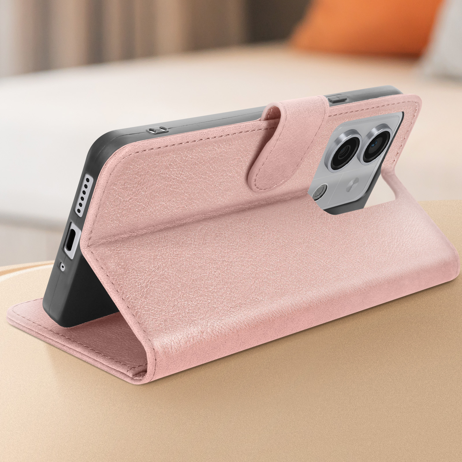 Custodia per telefono rosa, aperta per rivelare il telefono, posta su superficie dorata.