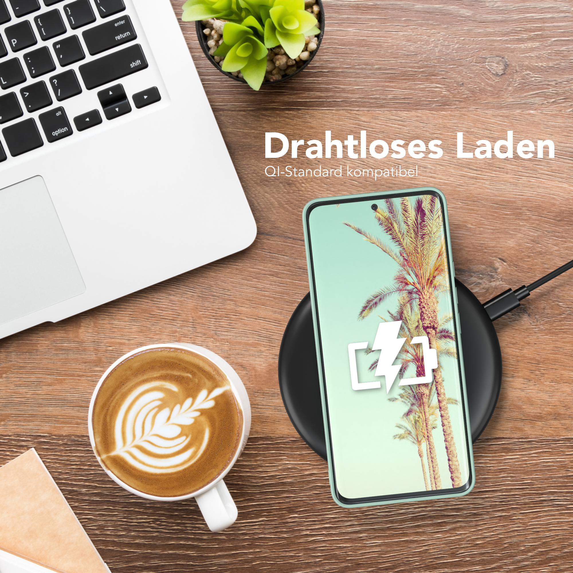 Ein Telefon mit Ladesymbol auf einem kabellosen Ladegerät, ein Laptop und eine Kaffeetasse auf einem Holztisch.