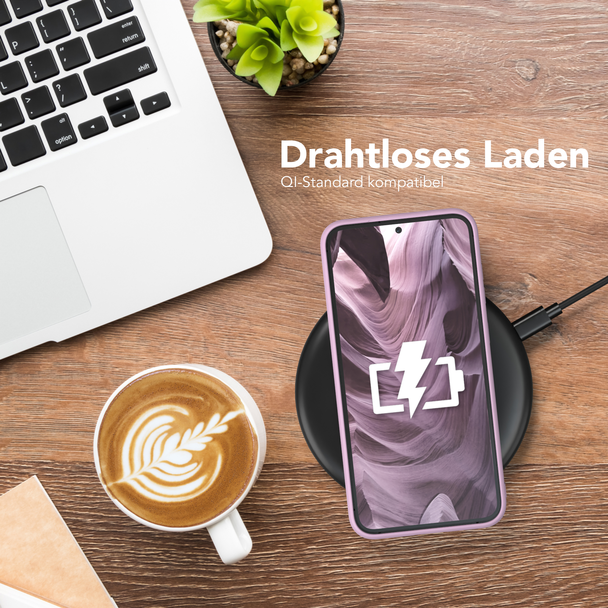 Laptop, Kaffee und Telefon, das auf einem Holztisch aufgeladen wird. Im Hintergrund eine Pflanze.