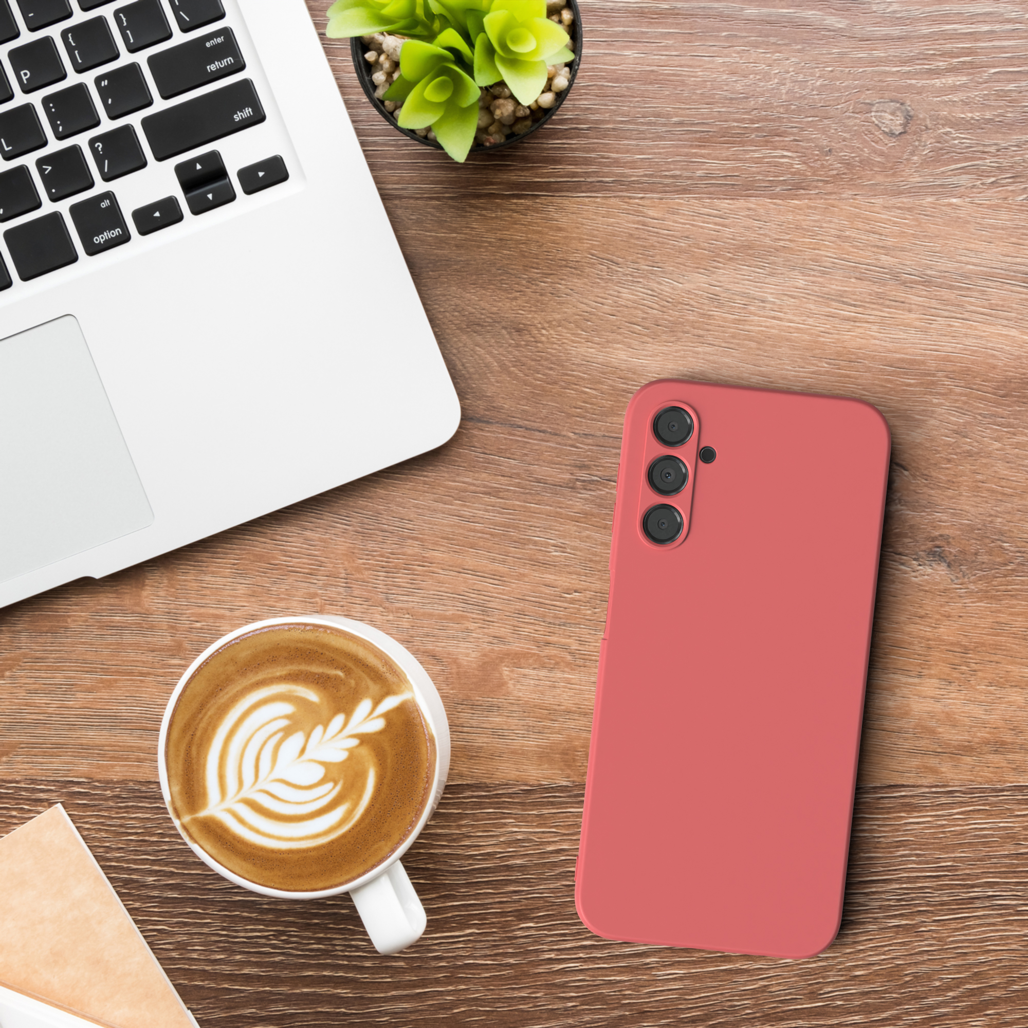 Ein weißer Laptop, ein rotes Telefon und eine Kaffeetasse auf einem Holztisch.