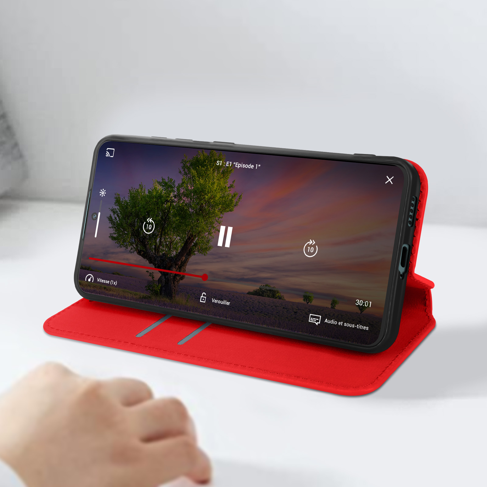 Un telefono che mostra un video su una custodia rossa. Una mano sta toccando lo schermo.