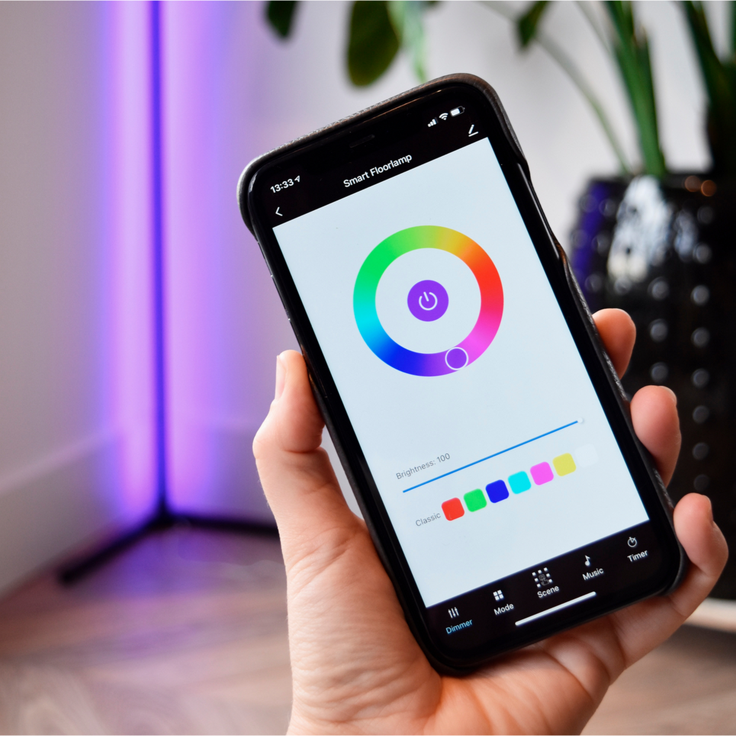Ręka trzymająca smartfon z interfejsem aplikacji inteligentnej lampy podłogowej z opcjami kolorów.