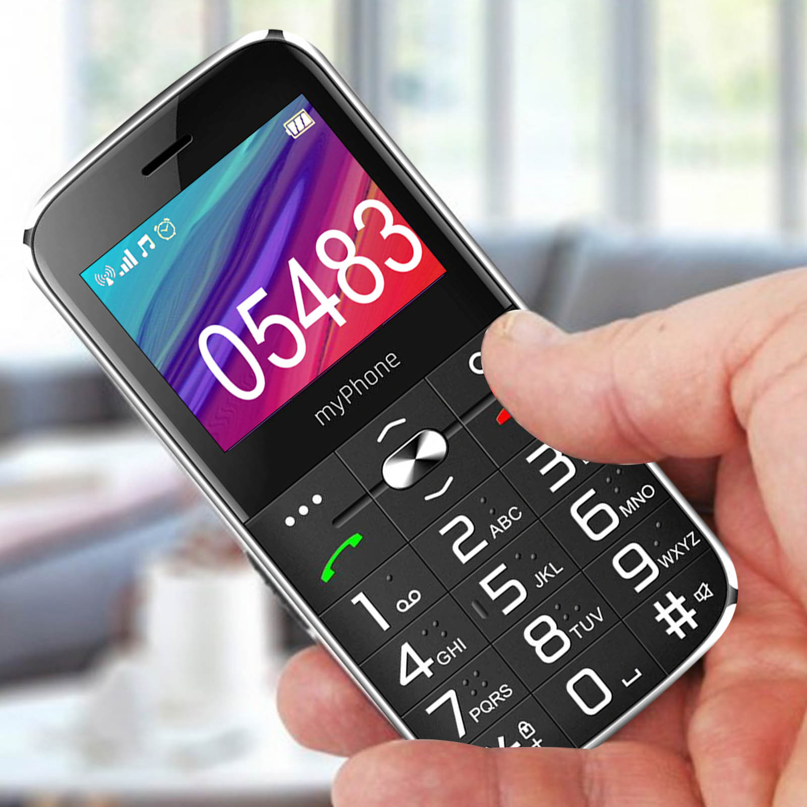 Ein schwarzes und silbernes Mobiltelefon wird von einer Hand gehalten. Der Bildschirm zeigt die Nummer 05483.