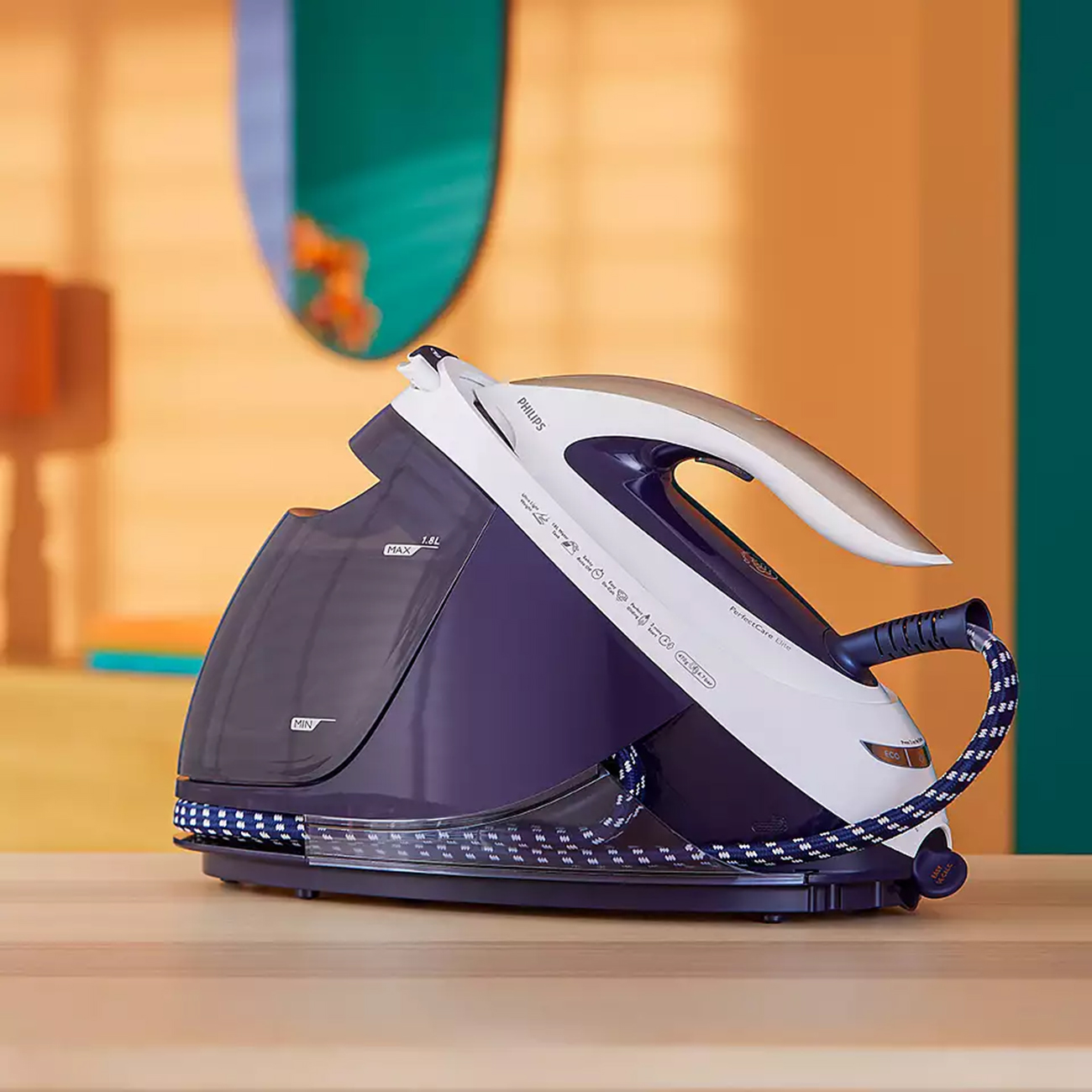Ein weißes und violettes Bügeleisen mit blauem Kabel. Es steht auf einem Holztisch, mit Hintergrund.