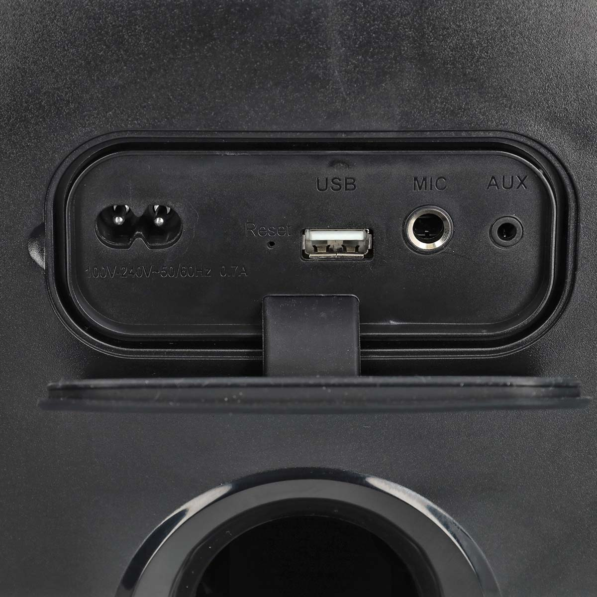 Gros plan sur le panneau arrière d'un haut-parleur, montrant les ports d'alimentation, USB, micro et auxiliaire, et un bouton de réinitialisation.