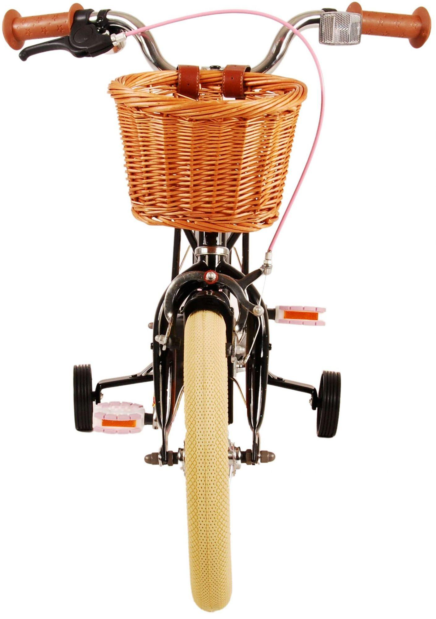 Ein Kinderfahrrad mit Korb und Stützrädern. Brauner Korb, rosa Kabel.