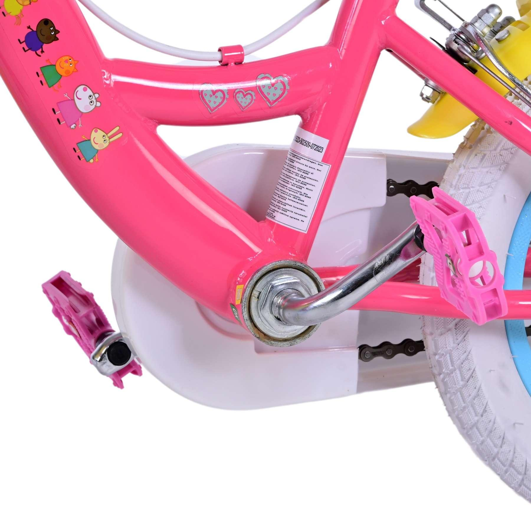 Rosa Kinderfahrradrahmen, rosa Pedale, weißer Kettenschutz und Zeichentrickbilder.