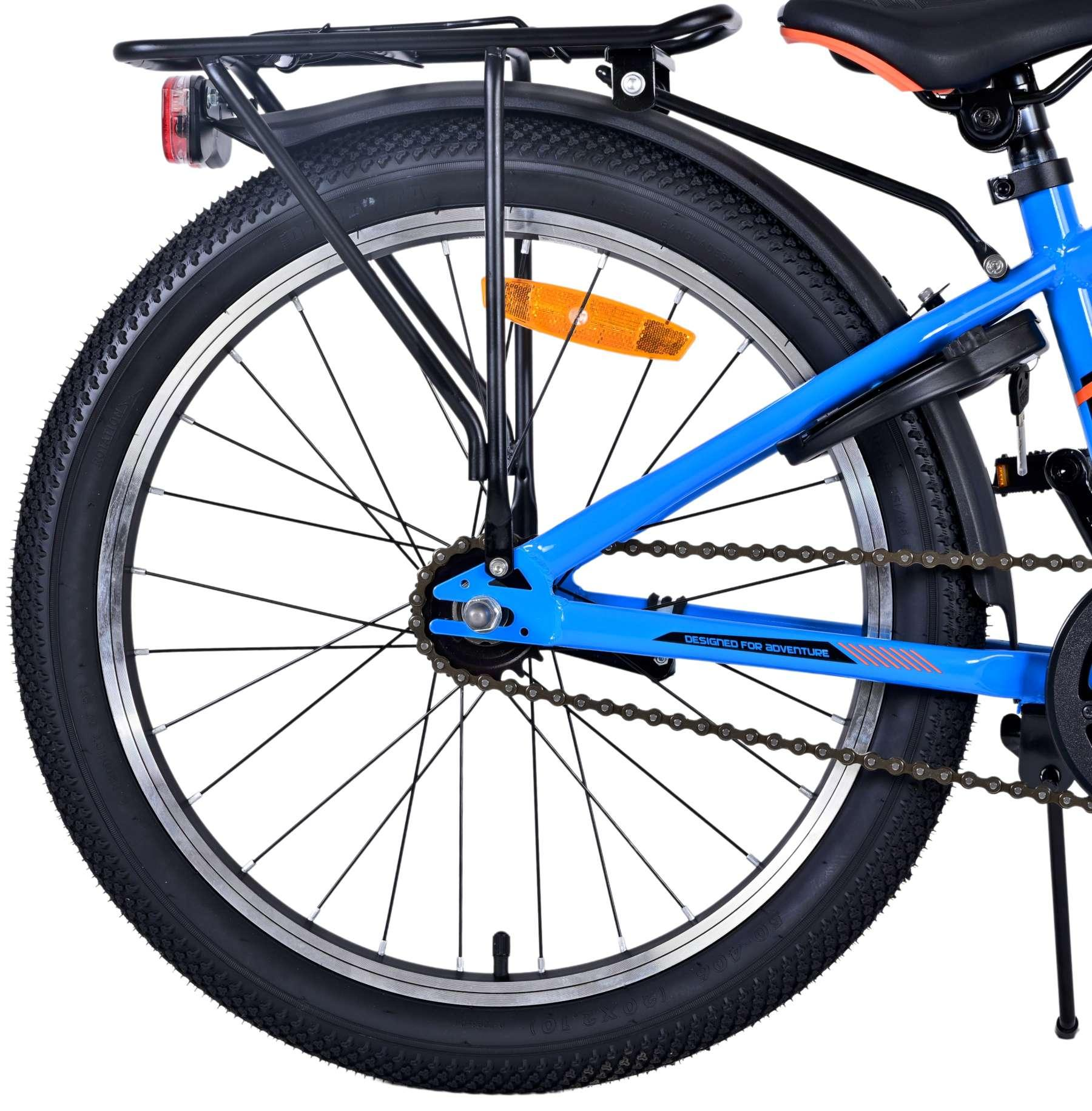 Hinterrad eines blauen Fahrrads mit schwarzem Gepäckträger und dem Text "DESIGNED FOR ADVENTURE".
