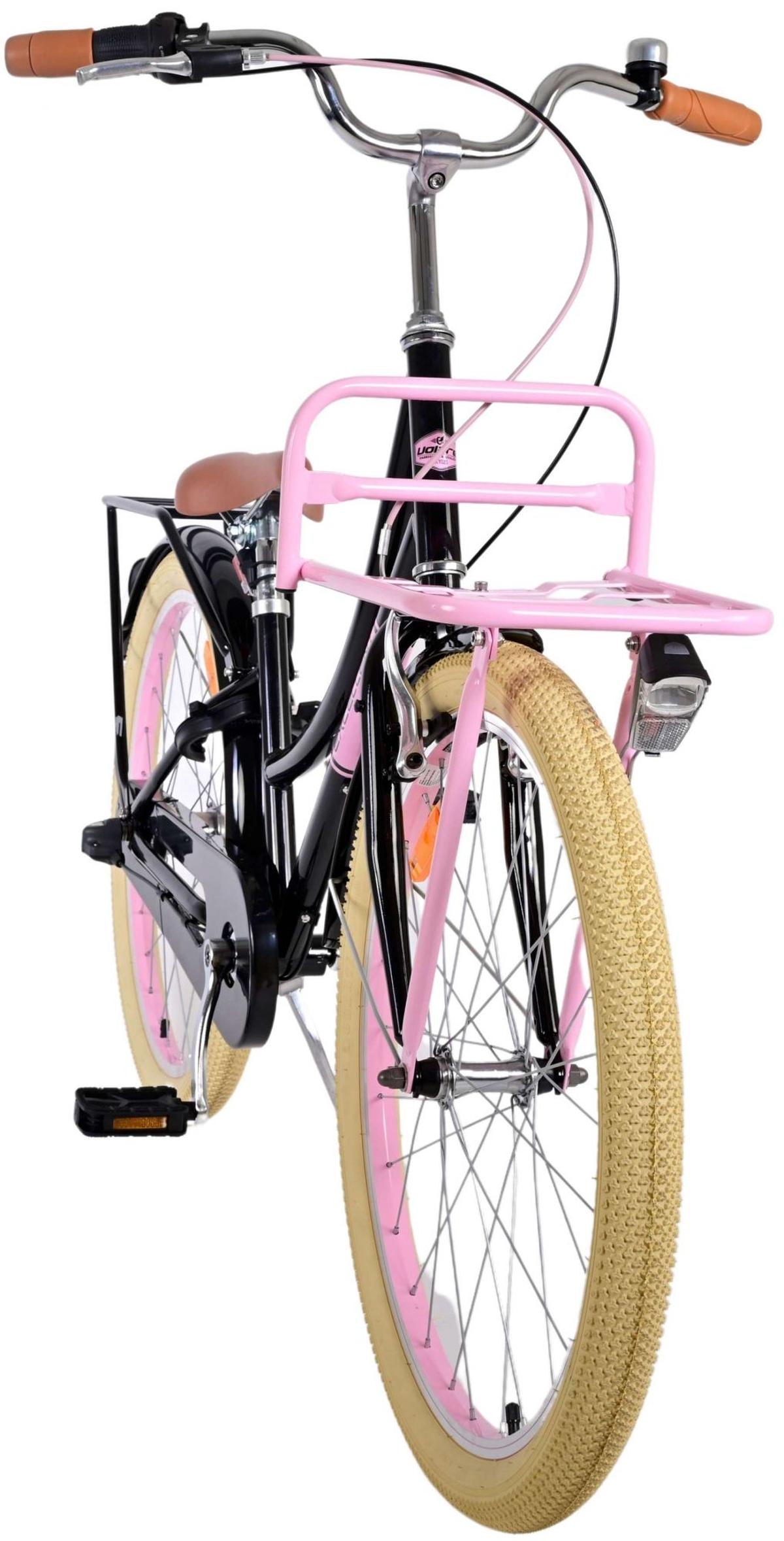 Ein schwarzes Fahrrad mit rosa Akzenten, einem vorderen Korb und einem braunen Sitz, aus einem niedrigen Winkel gesehen.