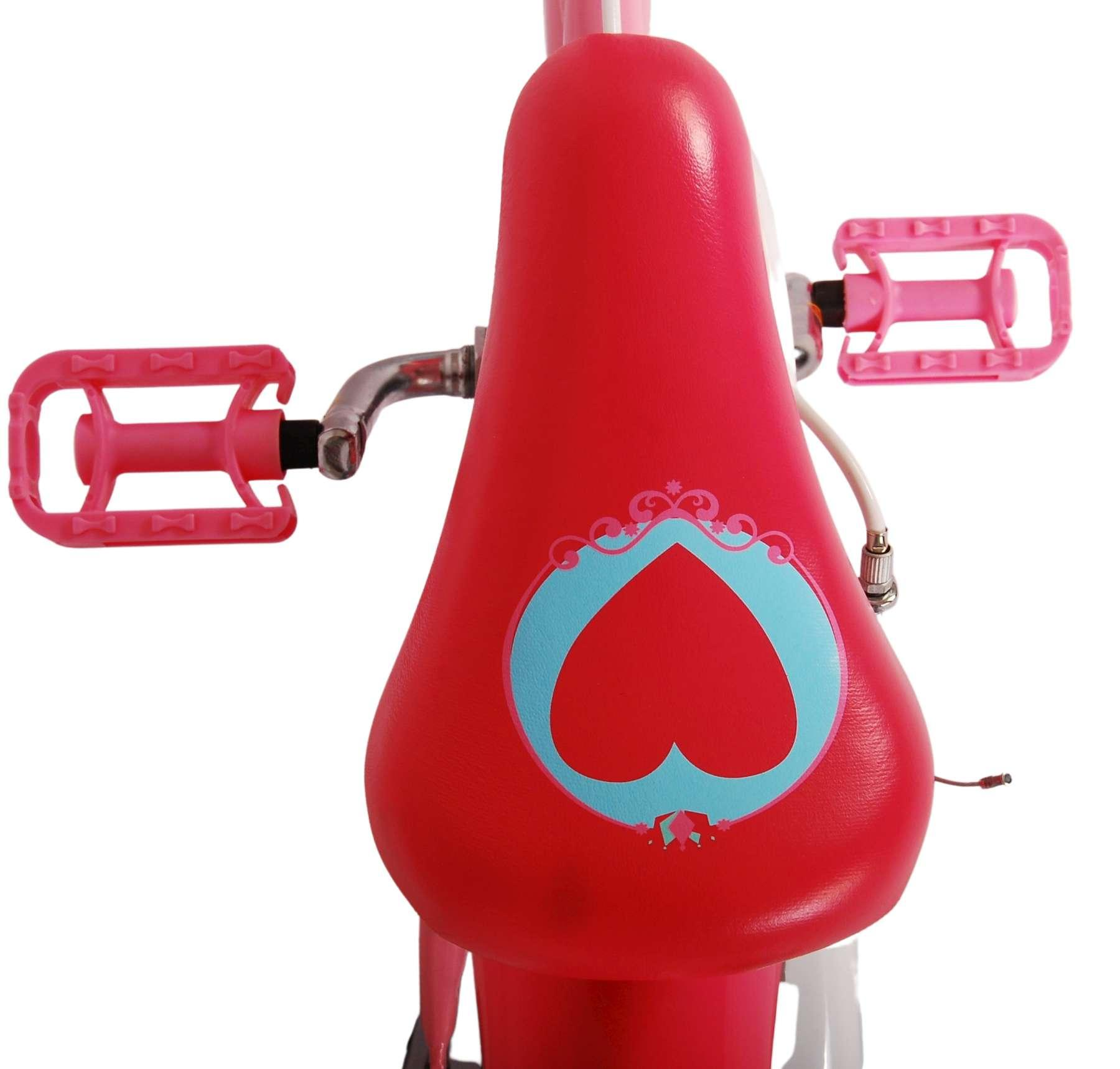 Nahaufnahme eines roten Fahrradsitzes mit Herzdesign und rosa Pedalen.