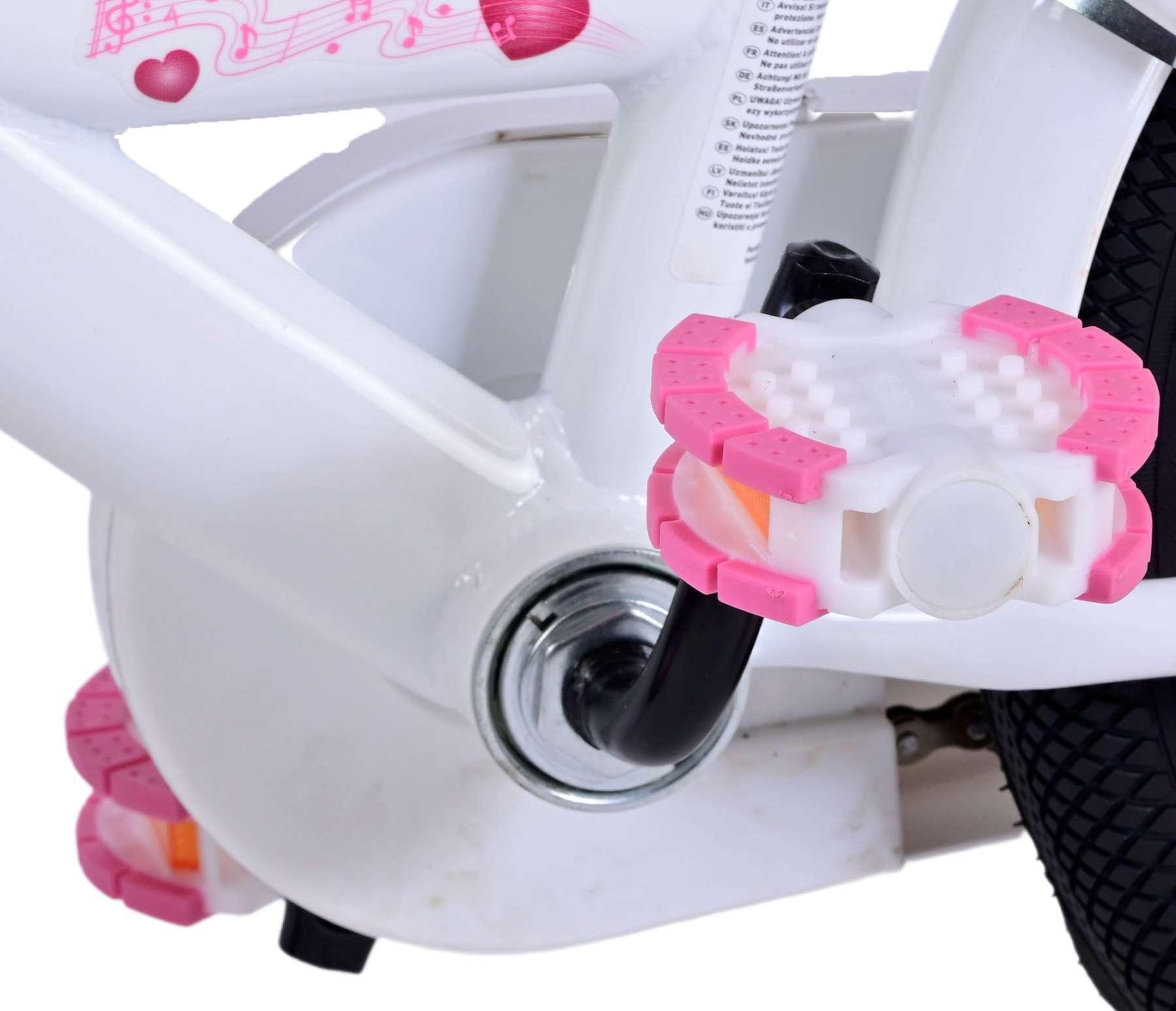 Nahaufnahme eines weißen Fahrradpedals mit rosa Akzenten. Das Pedal ist an einem weißen Rahmen befestigt.