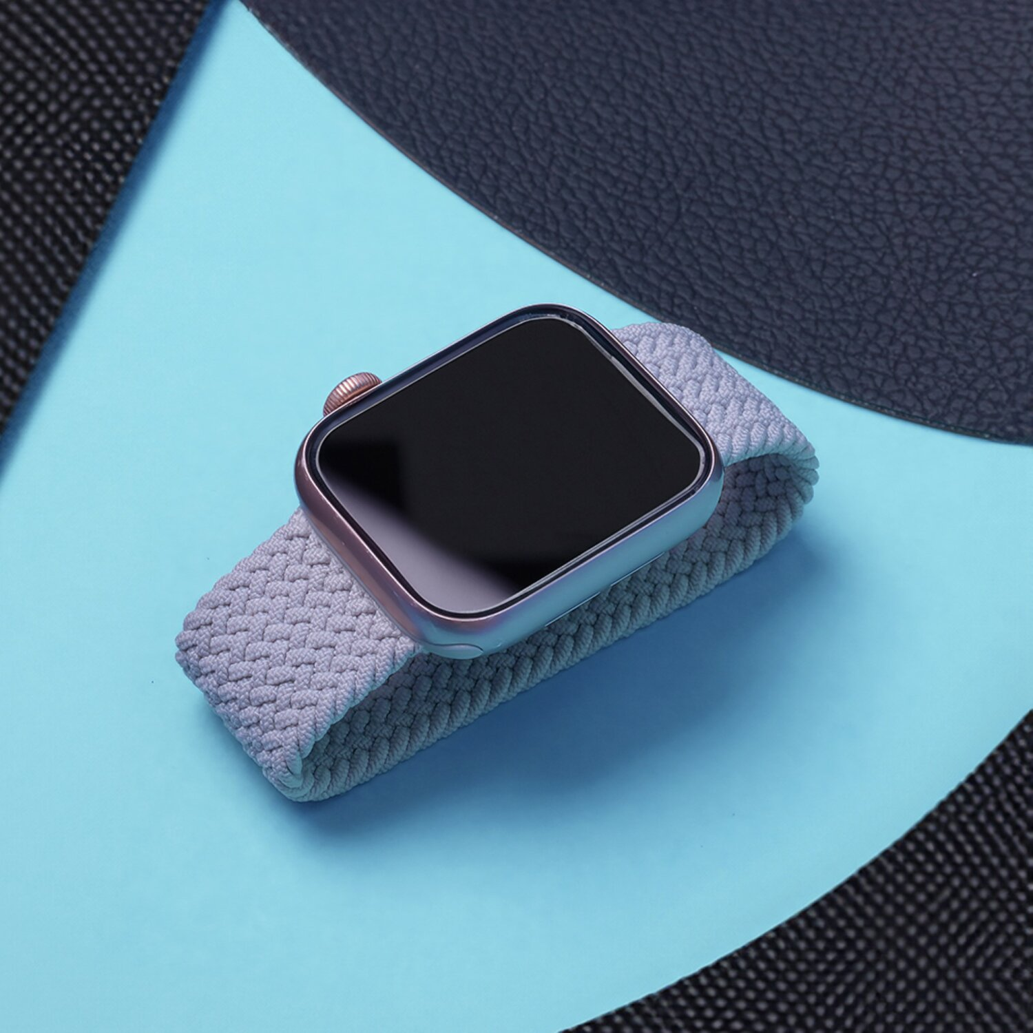 Eine Smartwatch mit grauem Armband auf blauem Untergrund mit schwarzem Hintergrund.