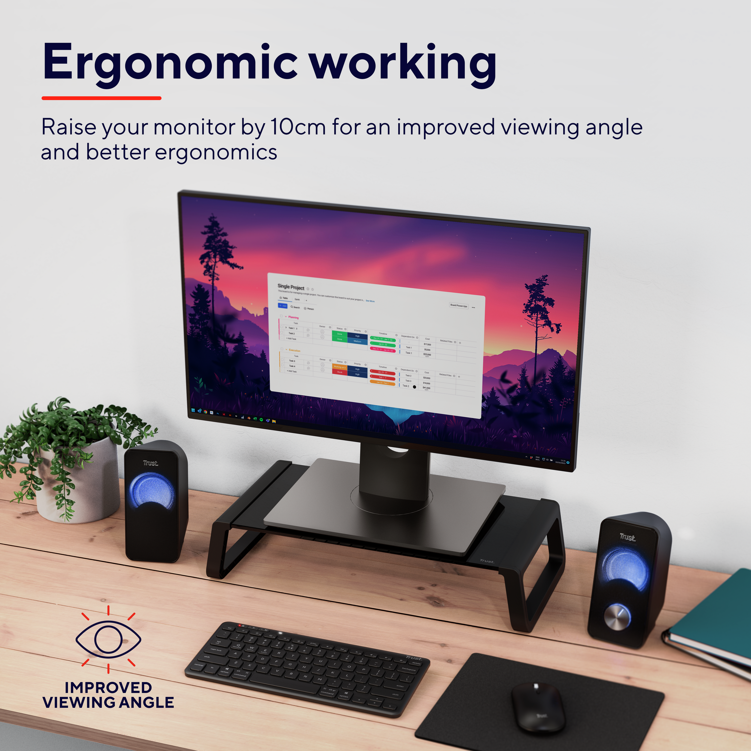 Ergonomiczne stanowisko pracy z monitorem na stojaku, klawiaturą, myszką i dwoma głośnikami. Tekst: poprawiony kąt widzenia.