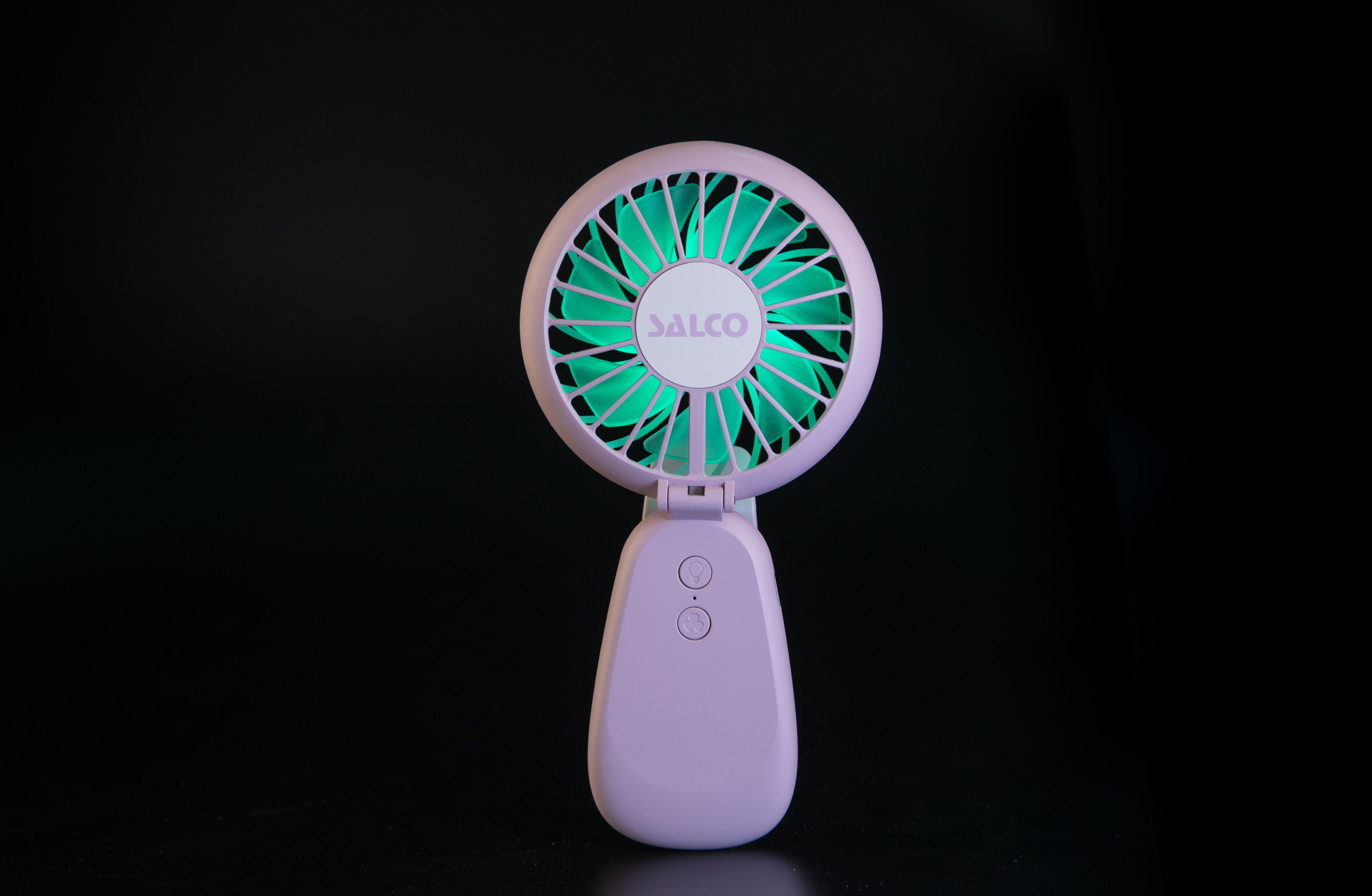 Ein tragbarer Ventilator mit hellviolettem Gehäuse und grünen Flügeln.