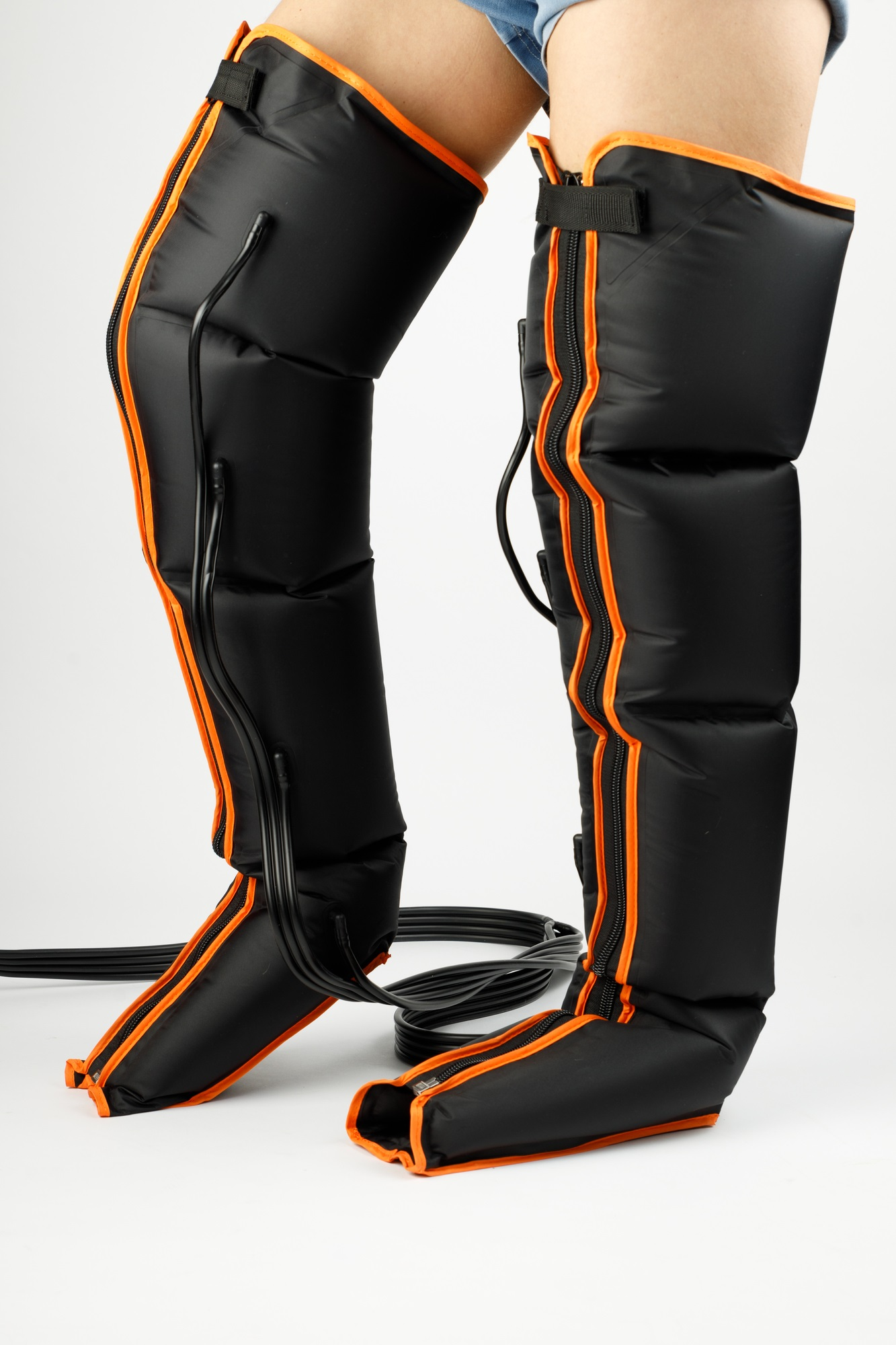 Person trägt schwarze und orangefarbene Kompressionsstiefel für die Beintherapie.