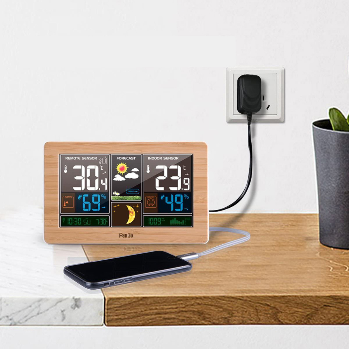 Digitale Wetterstation mit Display, Telefon und Ladegerät.