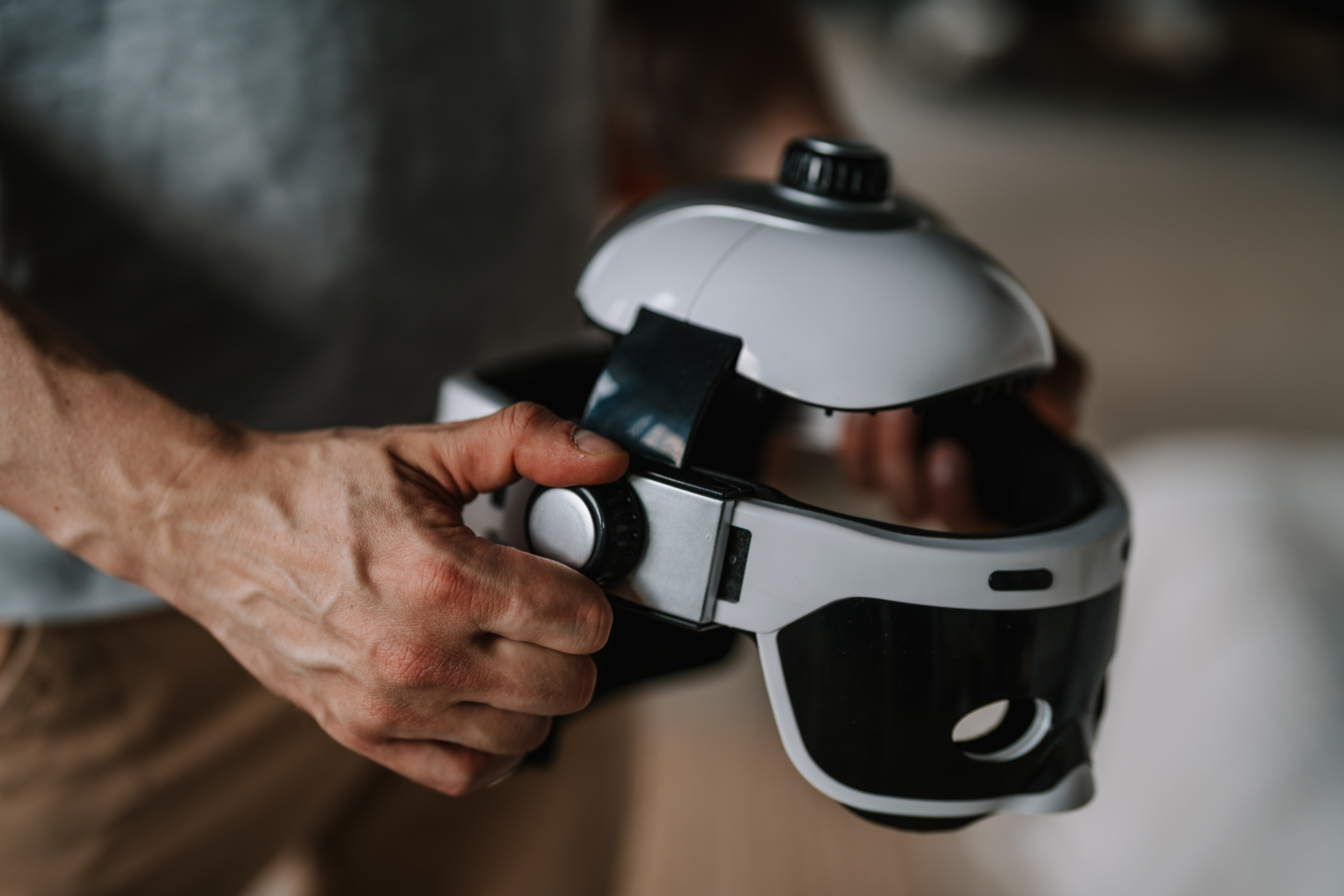 Person hält ein weißes und schwarzes VR-Headset und stellt ein Rad ein.